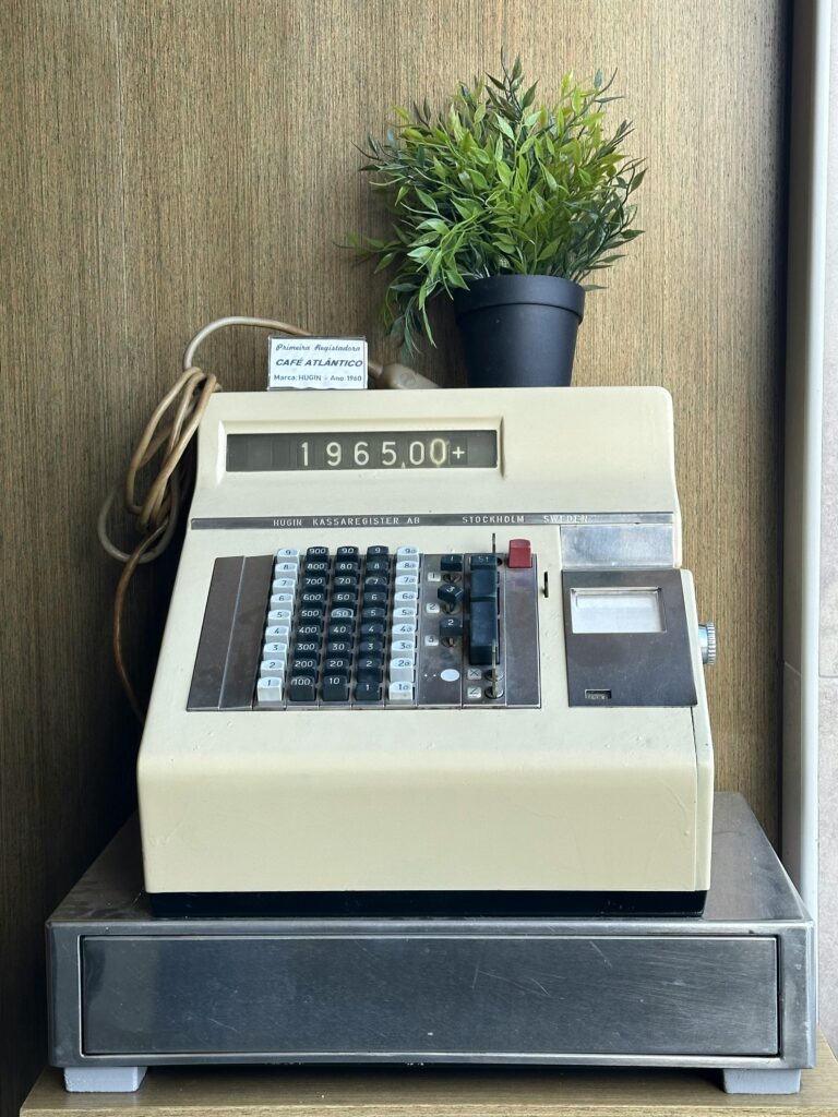 Retro cash register with a potted plant, ideal for vintage retail decor.